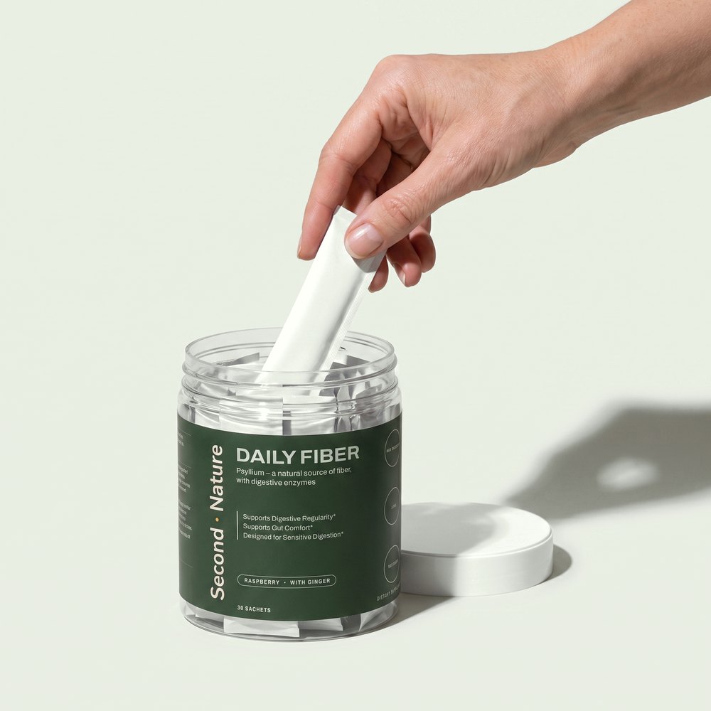 A hand lifting one sachet out of the Daily Fiber jar