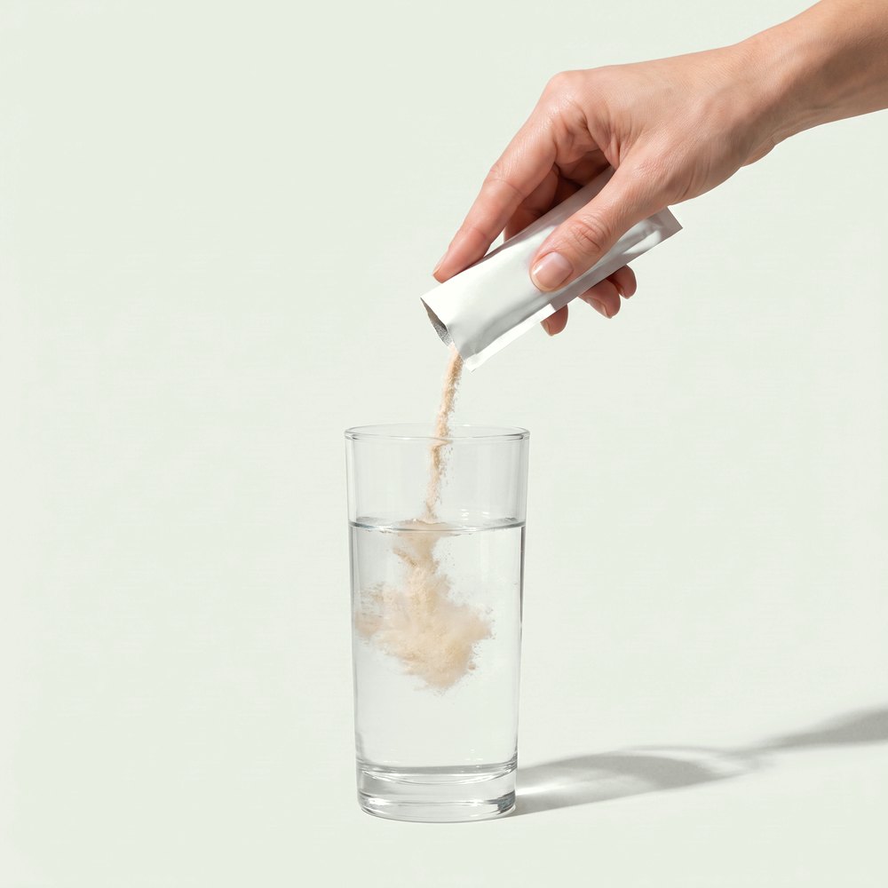 A sachet being poured into a tall glass of water